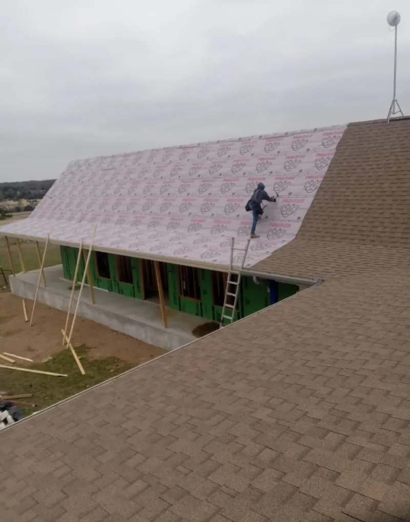 Worker preparing underlayment for a metal roof installation in Greenfield